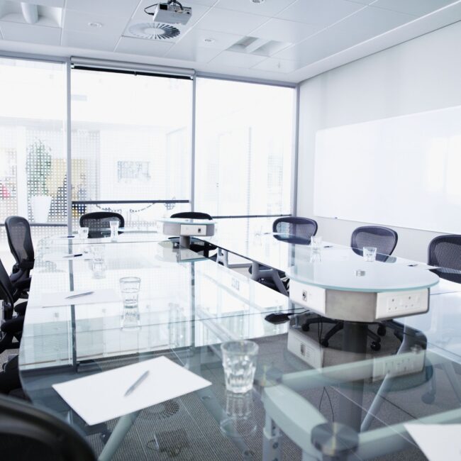 Bright, modern boardroom with empty chairs around a large table, ready for a meeting